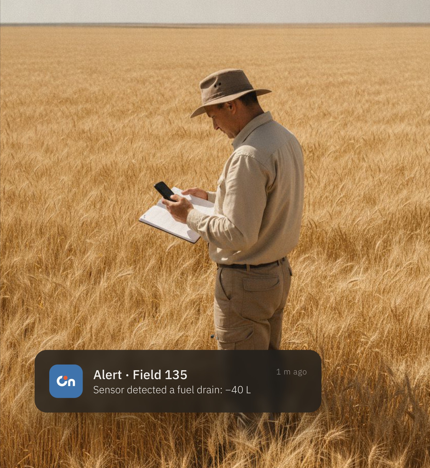 An agronomist in a wheat field checks an OnTrack alert on his phone